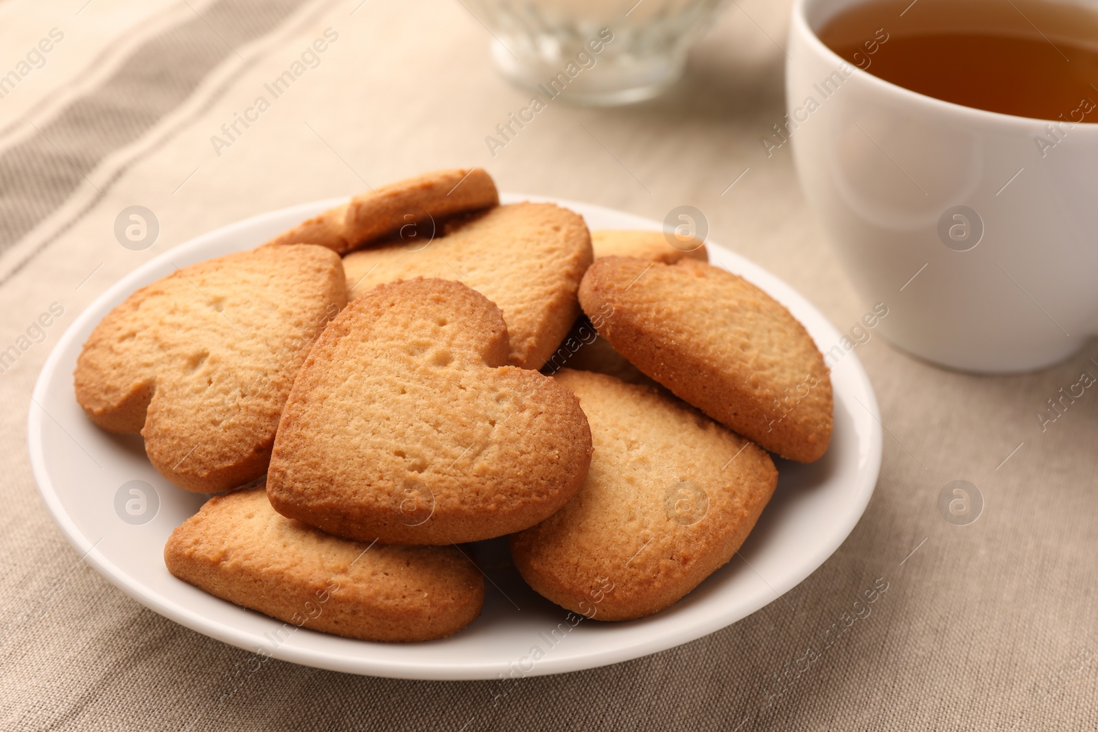 Photo of Heart shaped Danish butter cookies and tea on table, closeup