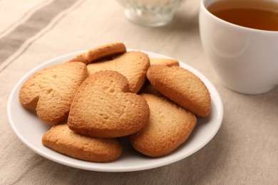 Photo of Heart shaped Danish butter cookies and tea on table, closeup