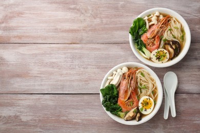 Delicious ramen with shrimps and mushrooms in bowls served on wooden table, flat lay with space for text. Noodle soup