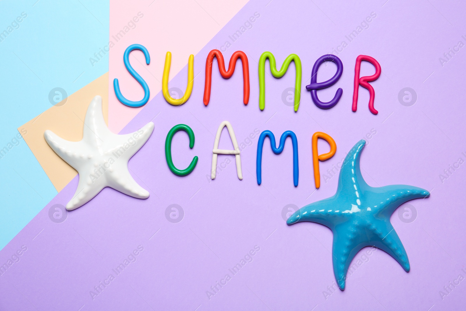 Photo of Text SUMMER CAMP made of modelling clay and decorative starfishes on color background, flat lay