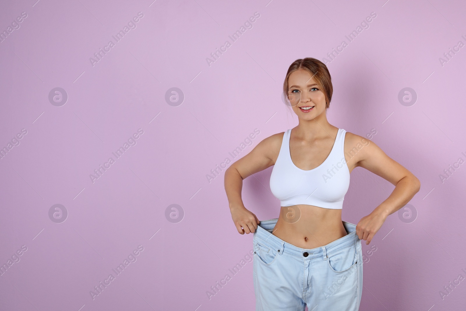 Photo of Young woman wearing oversize pants on color background. Healthy diet