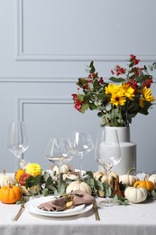 Beautiful autumn table setting with bouquet indoors. Plates, cutlery, glasses and floral decor