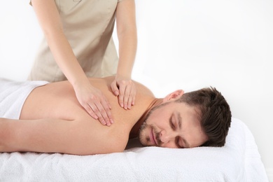 Handsome man receiving back massage on white background. Spa service