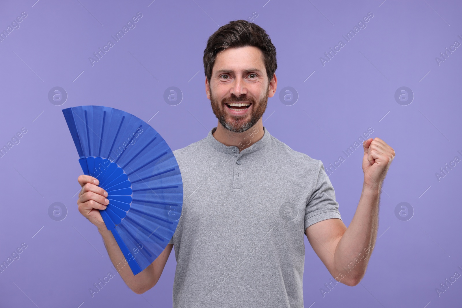 Photo of Emotional man holding hand fan on purple background