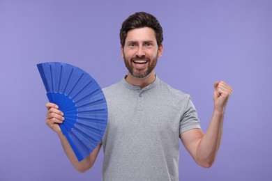 Photo of Emotional man holding hand fan on purple background