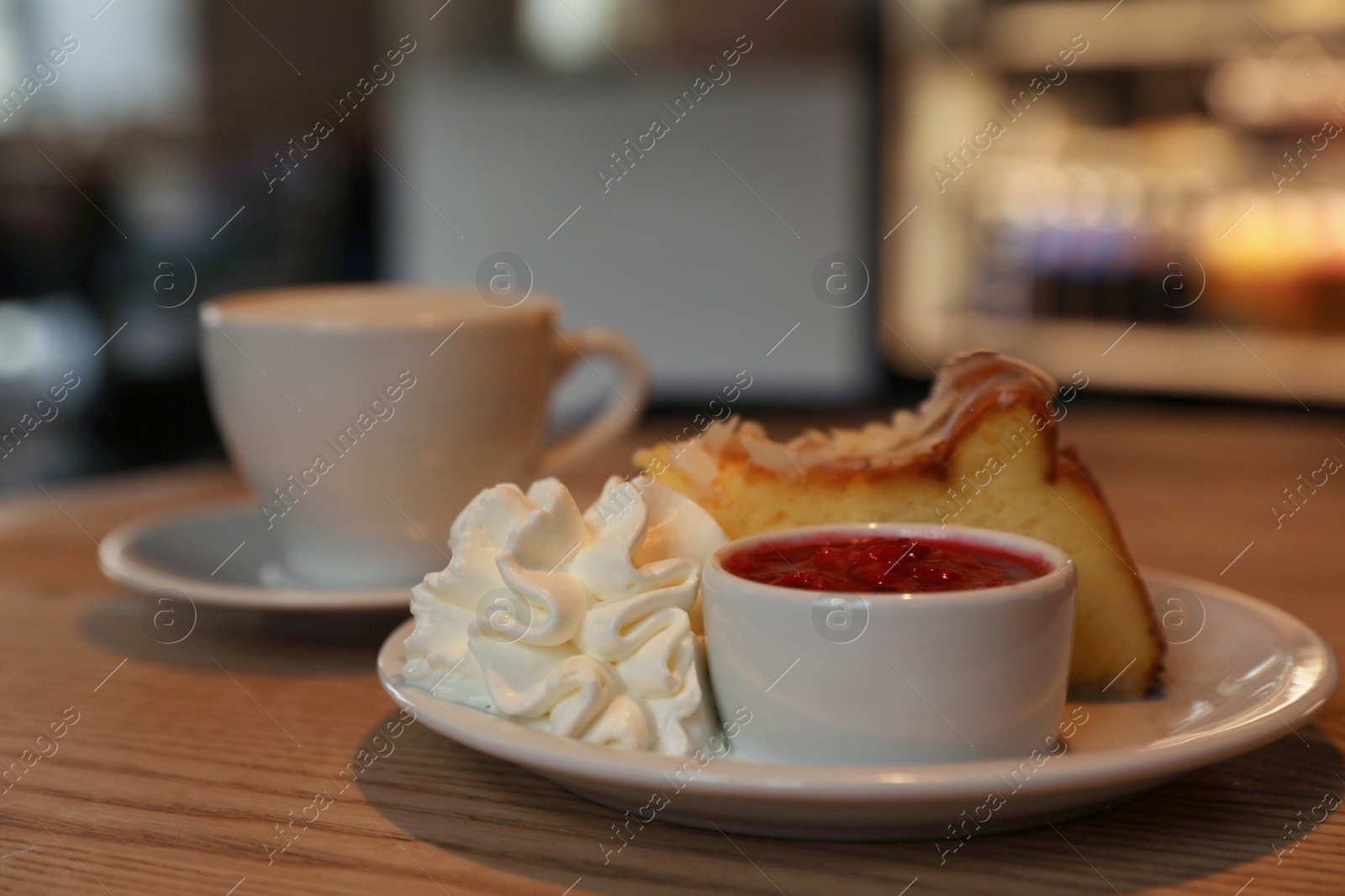 Photo of Delicious dessert and cup of aromatic coffee on wooden table in cafe, closeup