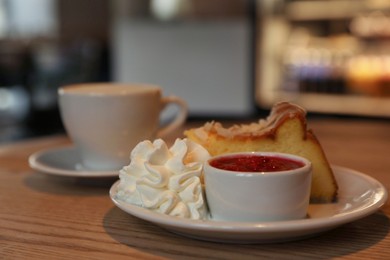 Delicious dessert and cup of aromatic coffee on wooden table in cafe, closeup