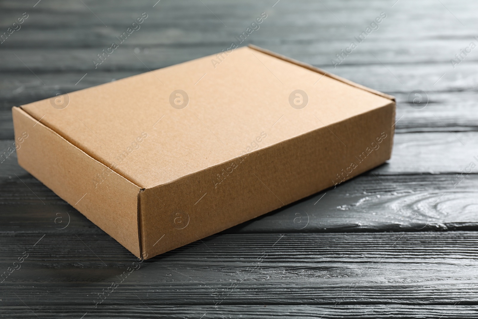 Photo of Closed cardboard box on dark wooden table