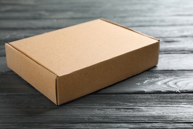 Photo of Closed cardboard box on dark wooden table