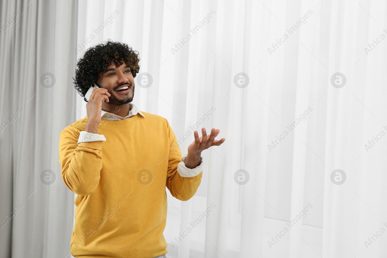 Photo of Handsome smiling man taking over smartphone indoors, space for text