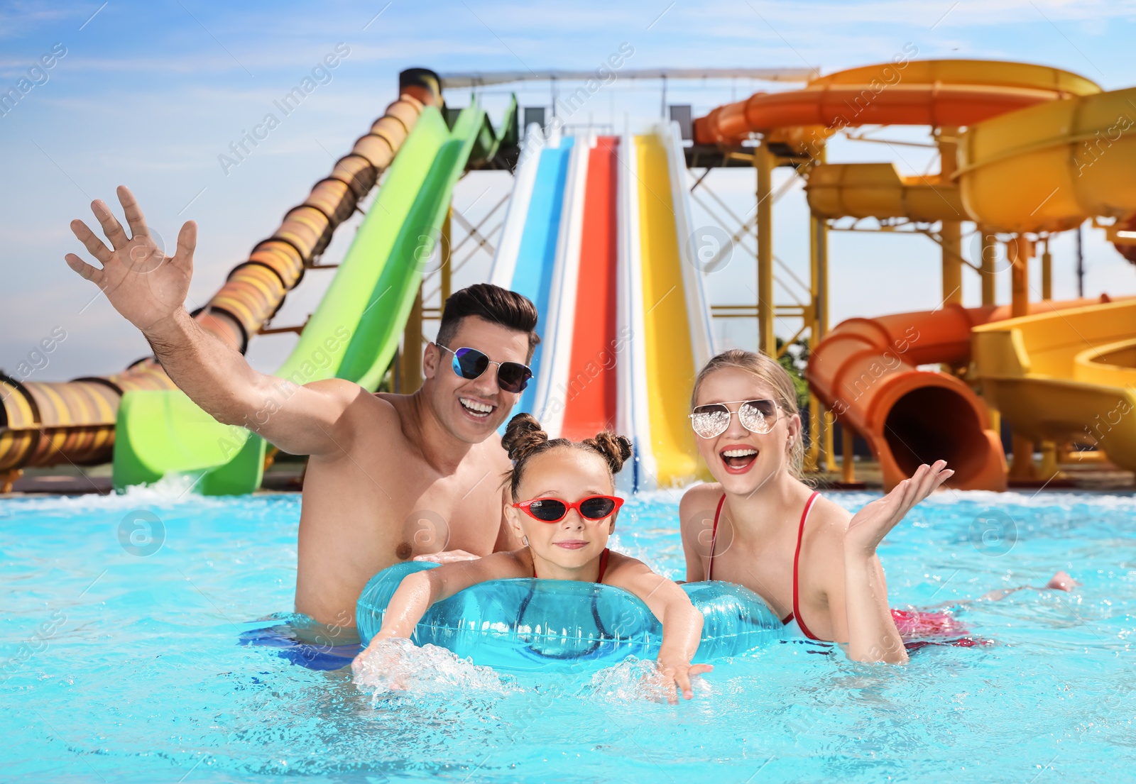 Photo of Happy family with inflatable ring in swimming pool at water park