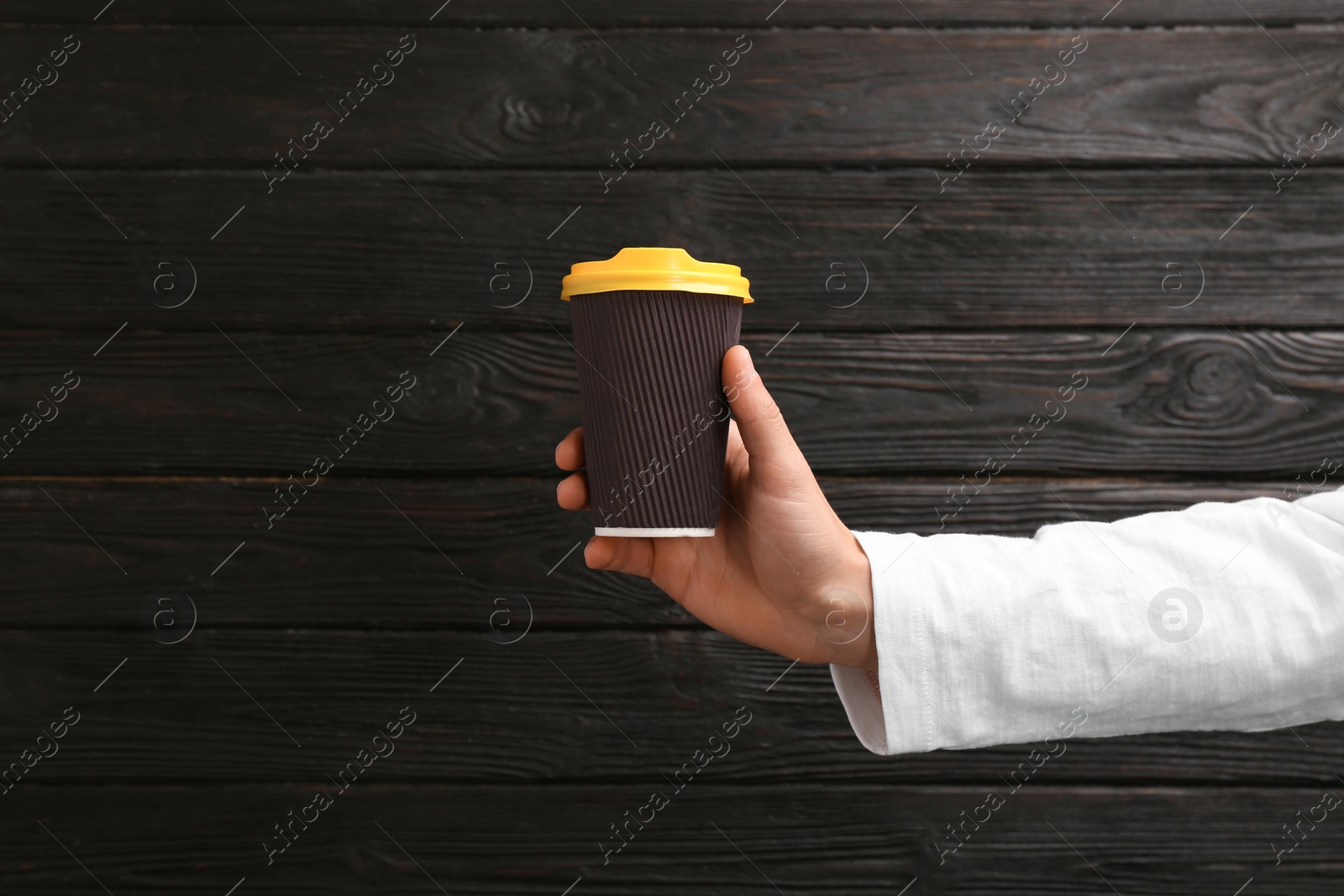 Photo of Man holding takeaway paper coffee cup on wooden background