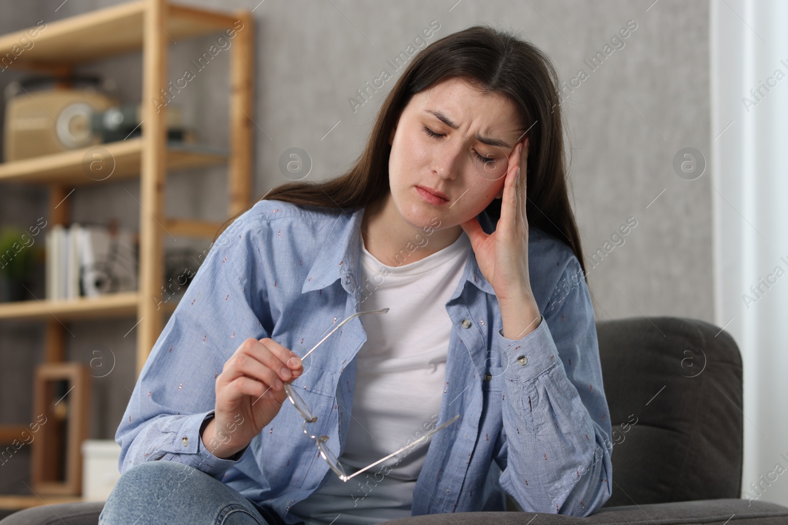 Photo of Overwhelmed woman with glasses sitting in armchair at home