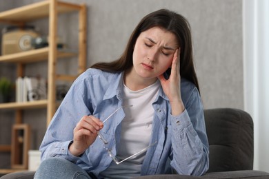 Photo of Overwhelmed woman with glasses sitting in armchair at home