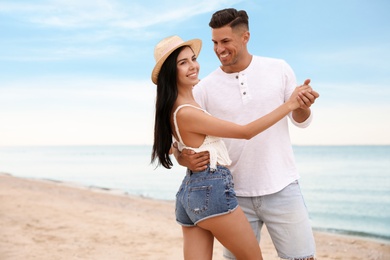 Lovely couple dancing on beach near sea