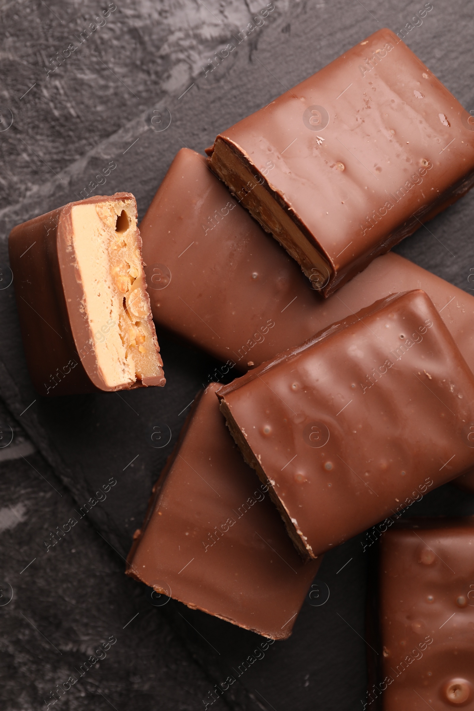 Photo of Tasty chocolate bars with nougat on gray table, top view