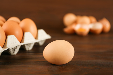 Raw chicken egg near carton tray on wooden table