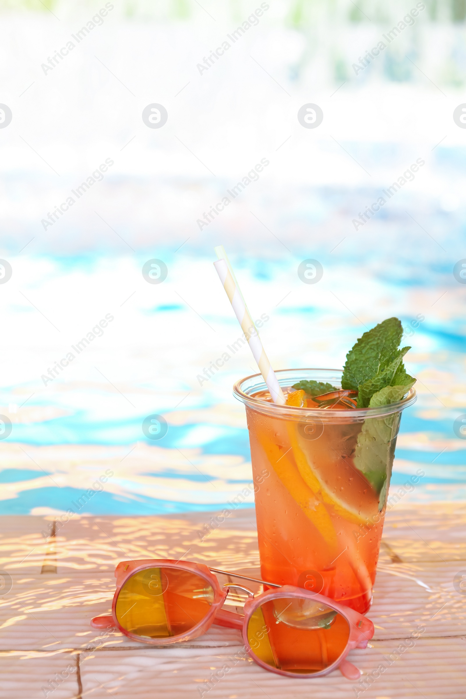 Photo of Delicious refreshing drink and sunglasses near swimming pool