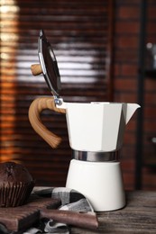 Photo of Brewing coffee. Moka pot and muffin on wooden table, closeup