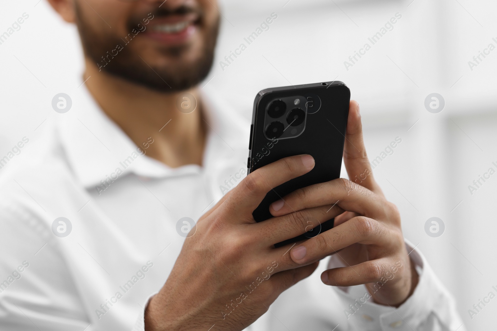 Photo of Young man using smartphone indoors, selective focus