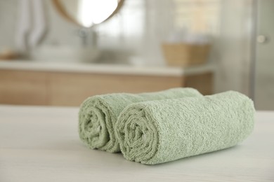 Photo of Clean rolled towels on white wooden table in bathroom