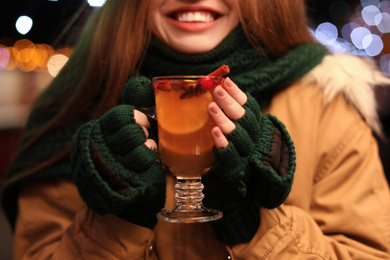 Photo of Woman with tasty mulled wine at winter fair, closeup