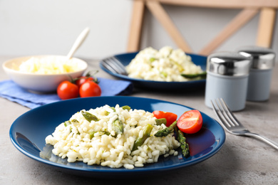 Photo of Delicious risotto with asparagus on grey table