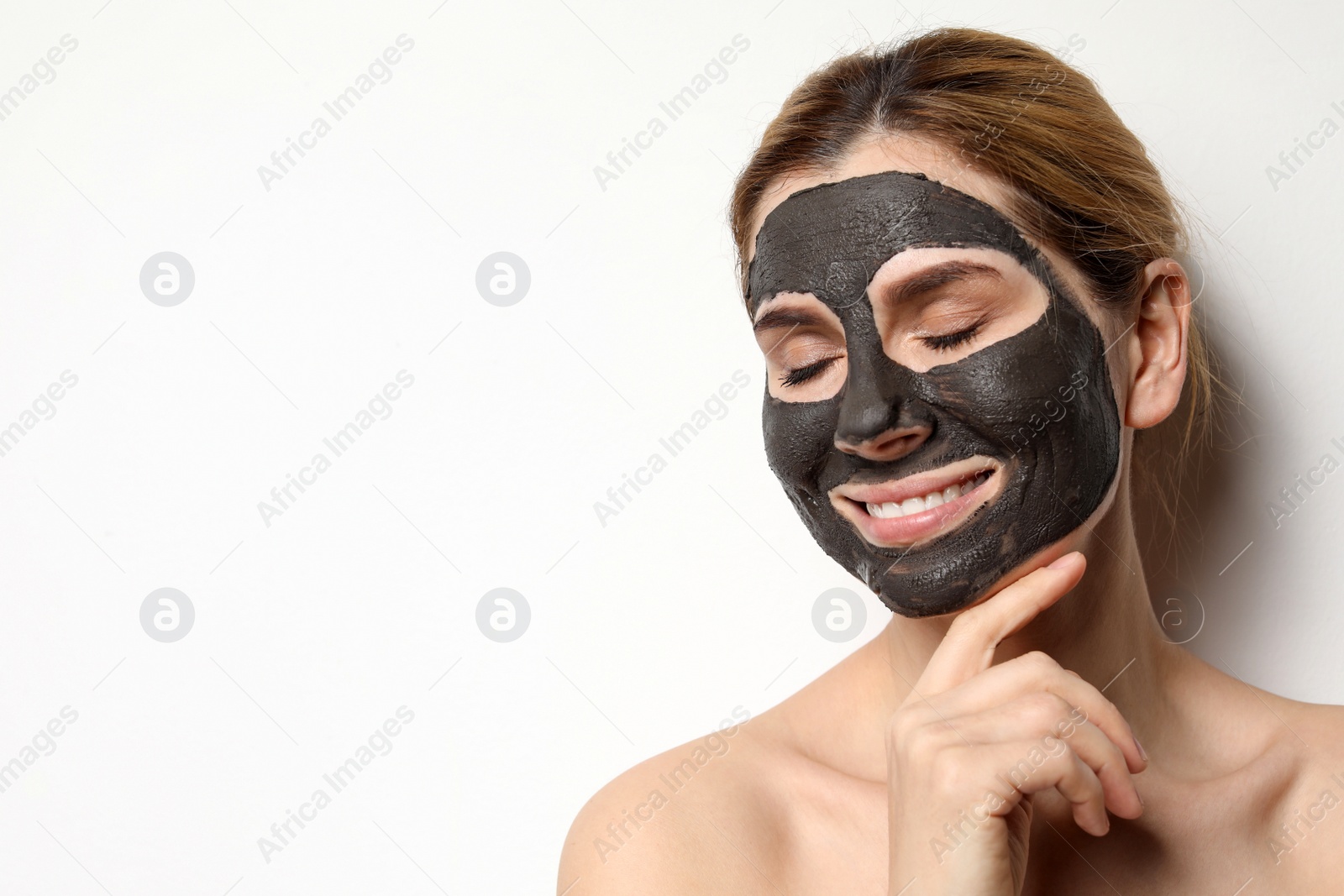 Photo of Beautiful woman with black mask on face against light background. Space for text