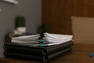 Stack of documents on wooden table in office. Space for text