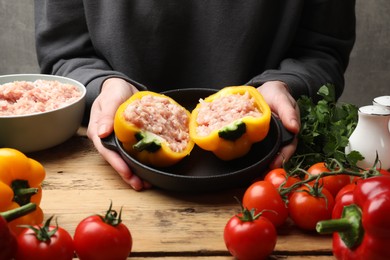 Woman making stuffed peppers with ground meat at wooden table, closeup