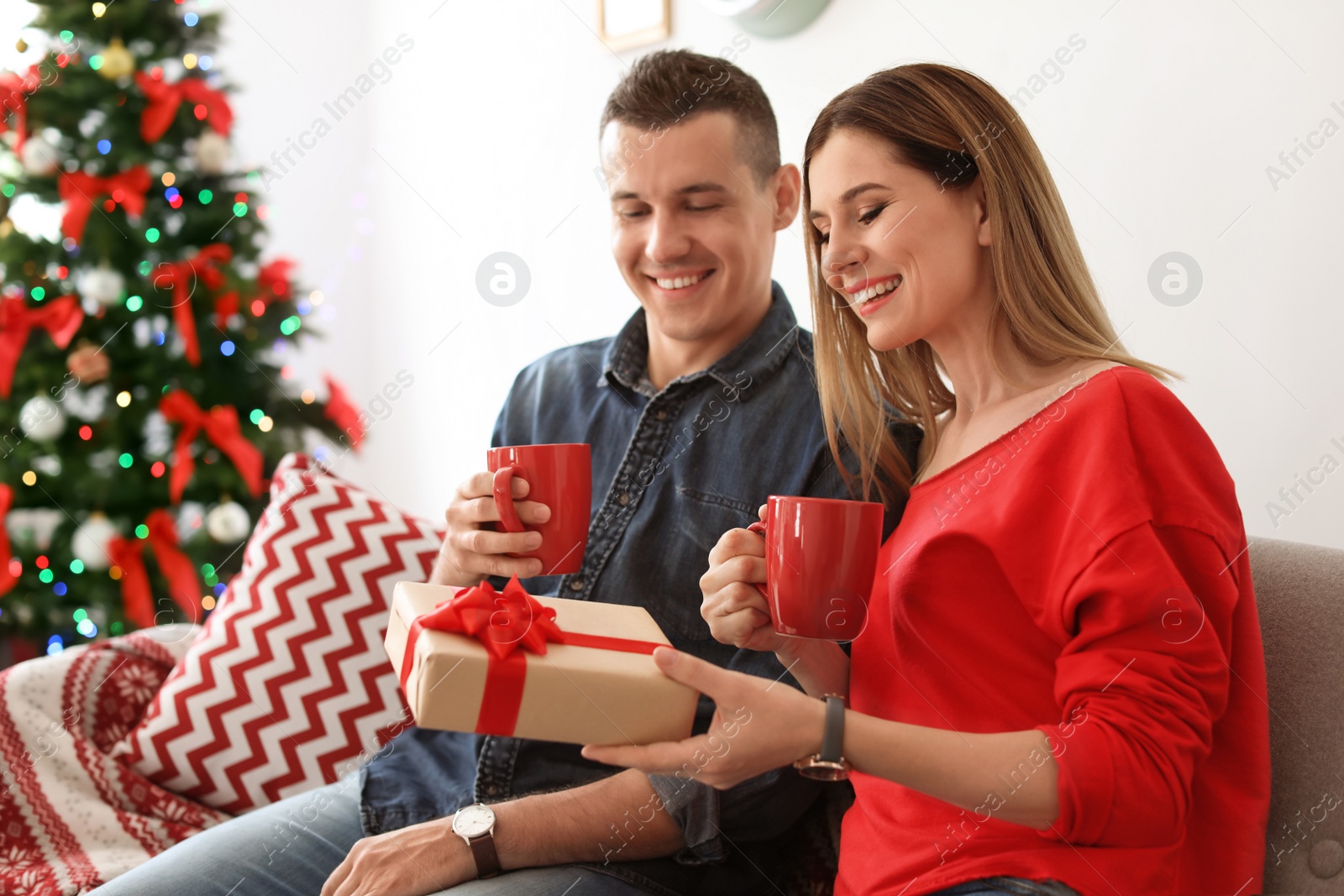 Photo of Young couple with Christmas gift at home
