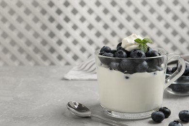 Photo of Delicious yogurt with blueberries served on grey marble table, space for text