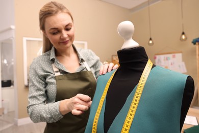 Photo of Dressmaker working with fabric in atelier, focus on mannequin