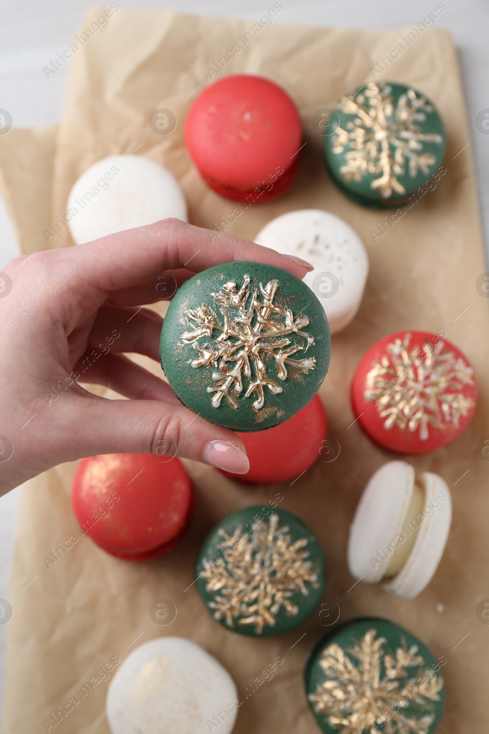 Photo of Woman with decorated Christmas macaron at table, top view