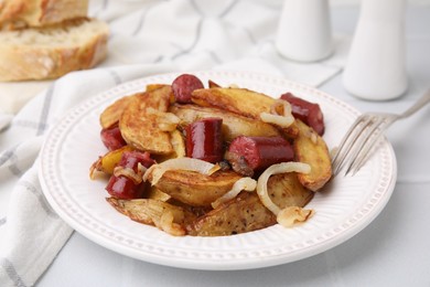 Photo of Delicious baked potato with thin dry smoked sausages and onion served on white table, closeup