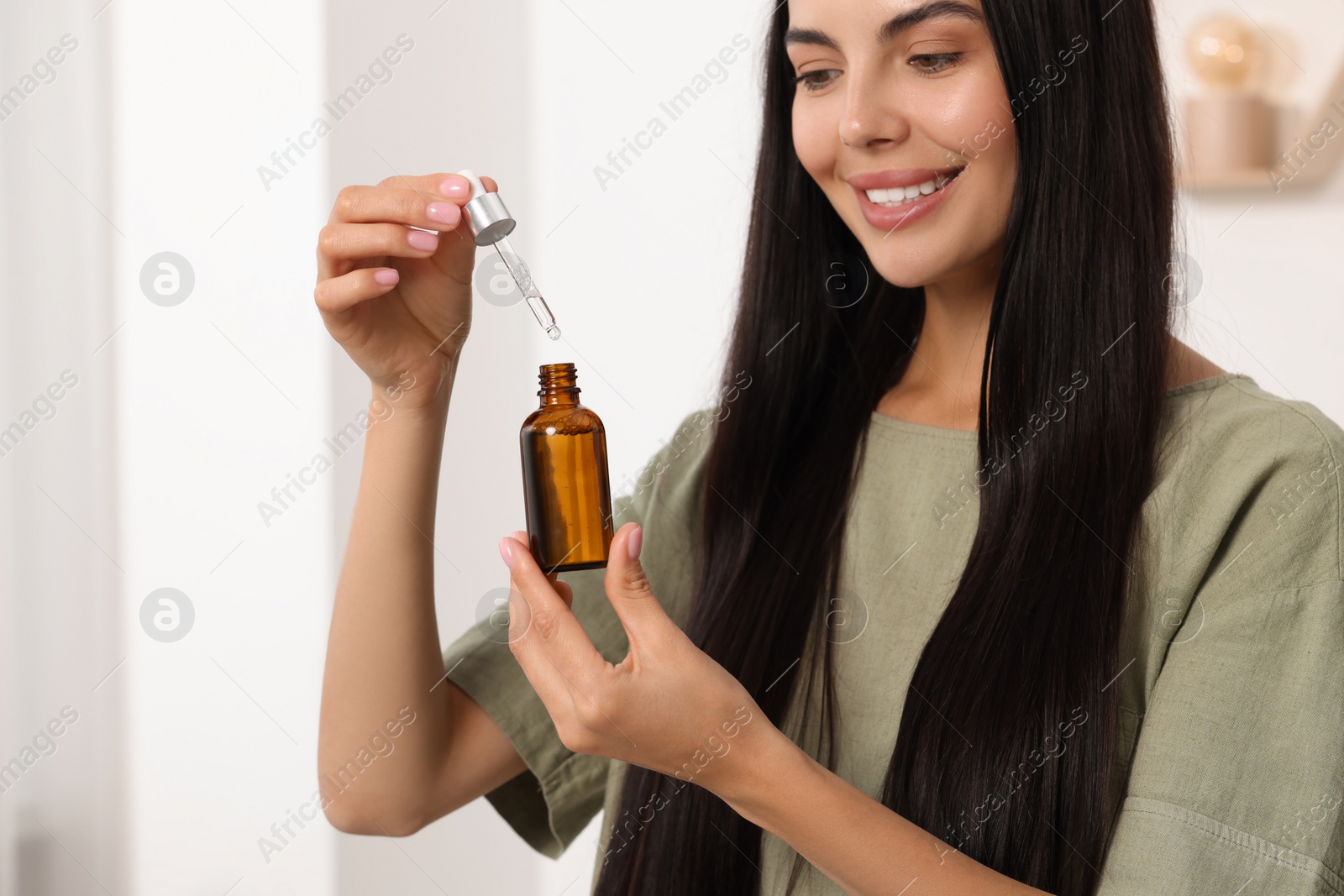 Photo of Beautiful woman holding bottle of serum in room. Cosmetic product