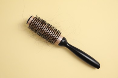 Photo of Professional brush with lost hair on beige background, top view
