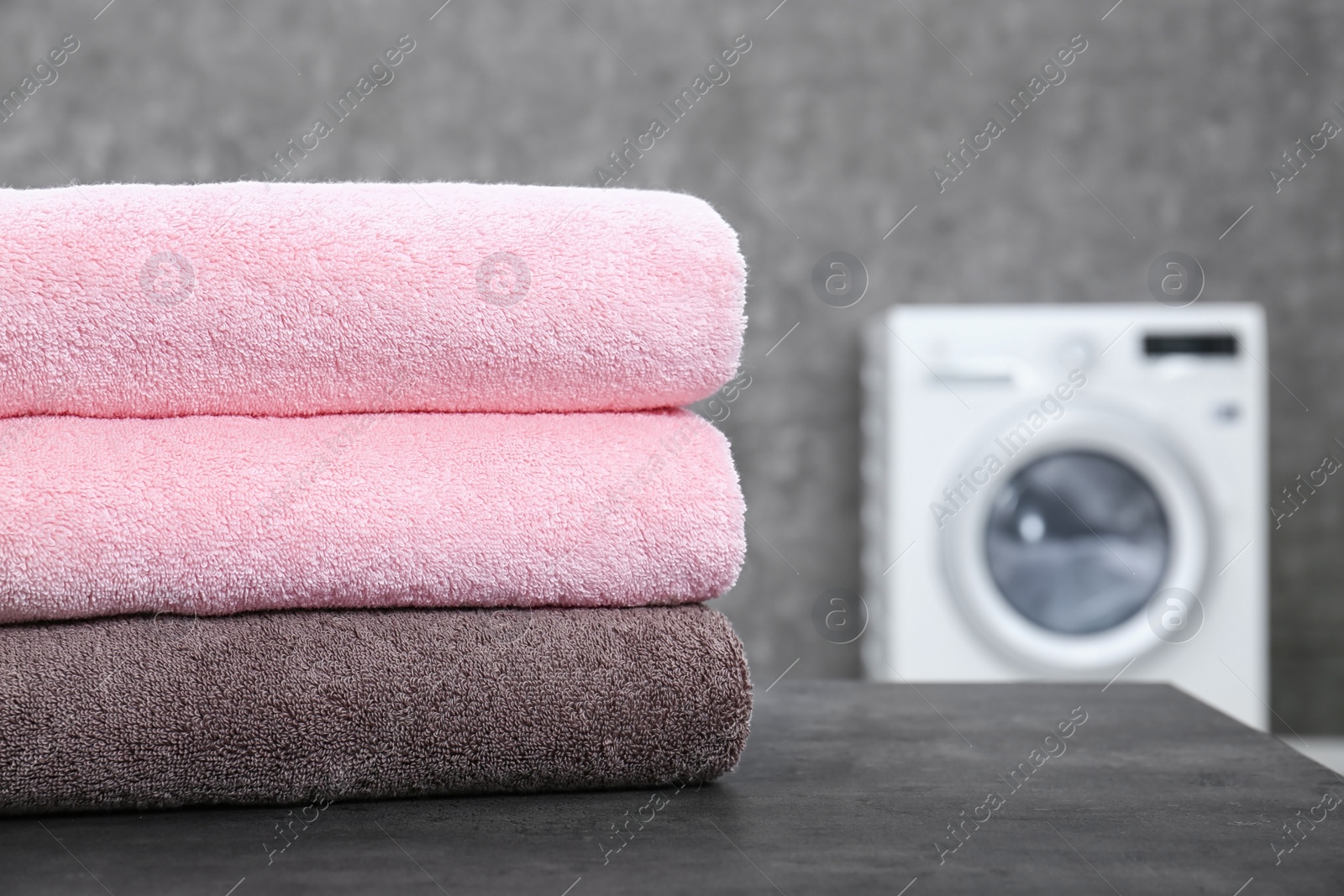 Photo of Stack of clean towels on table in laundry room, closeup. Space for text