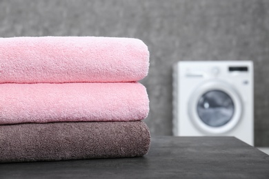 Stack of clean towels on table in laundry room, closeup. Space for text