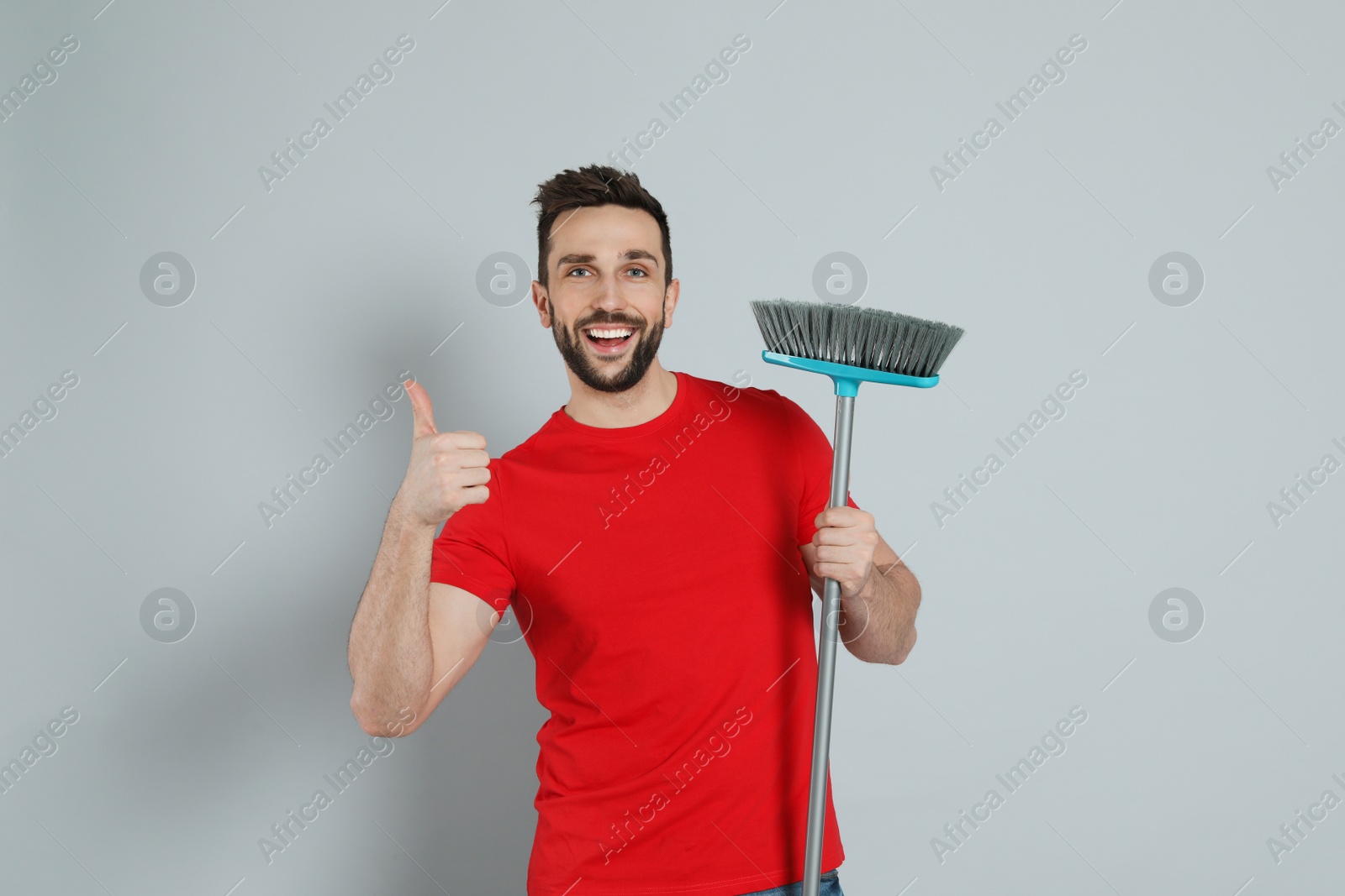 Photo of Handsome man with broom on grey background