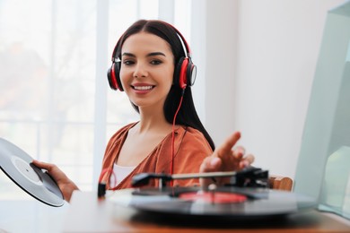 Photo of Woman listening to music with turntable at home