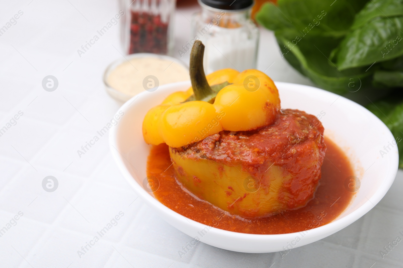 Photo of Delicious stuffed bell pepper on white tiled table. Space for text