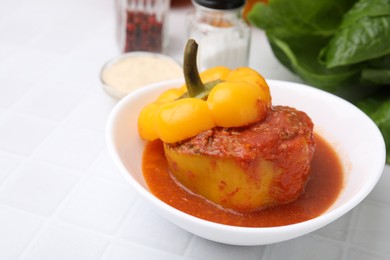 Photo of Delicious stuffed bell pepper on white tiled table. Space for text