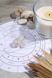 Photo of Natal chart, burning candle, astrology dices and stones on grey table, closeup