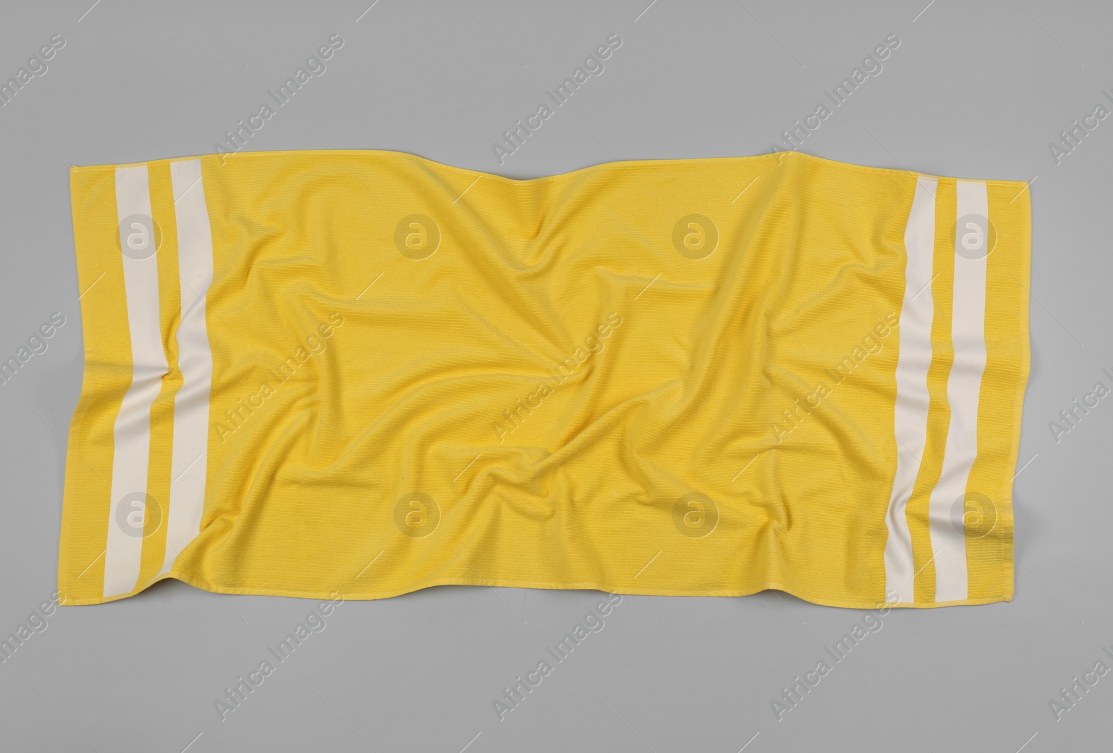 Photo of Crumpled yellow beach towel on light grey background, top view