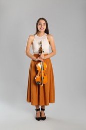 Photo of Beautiful woman with violin on grey background