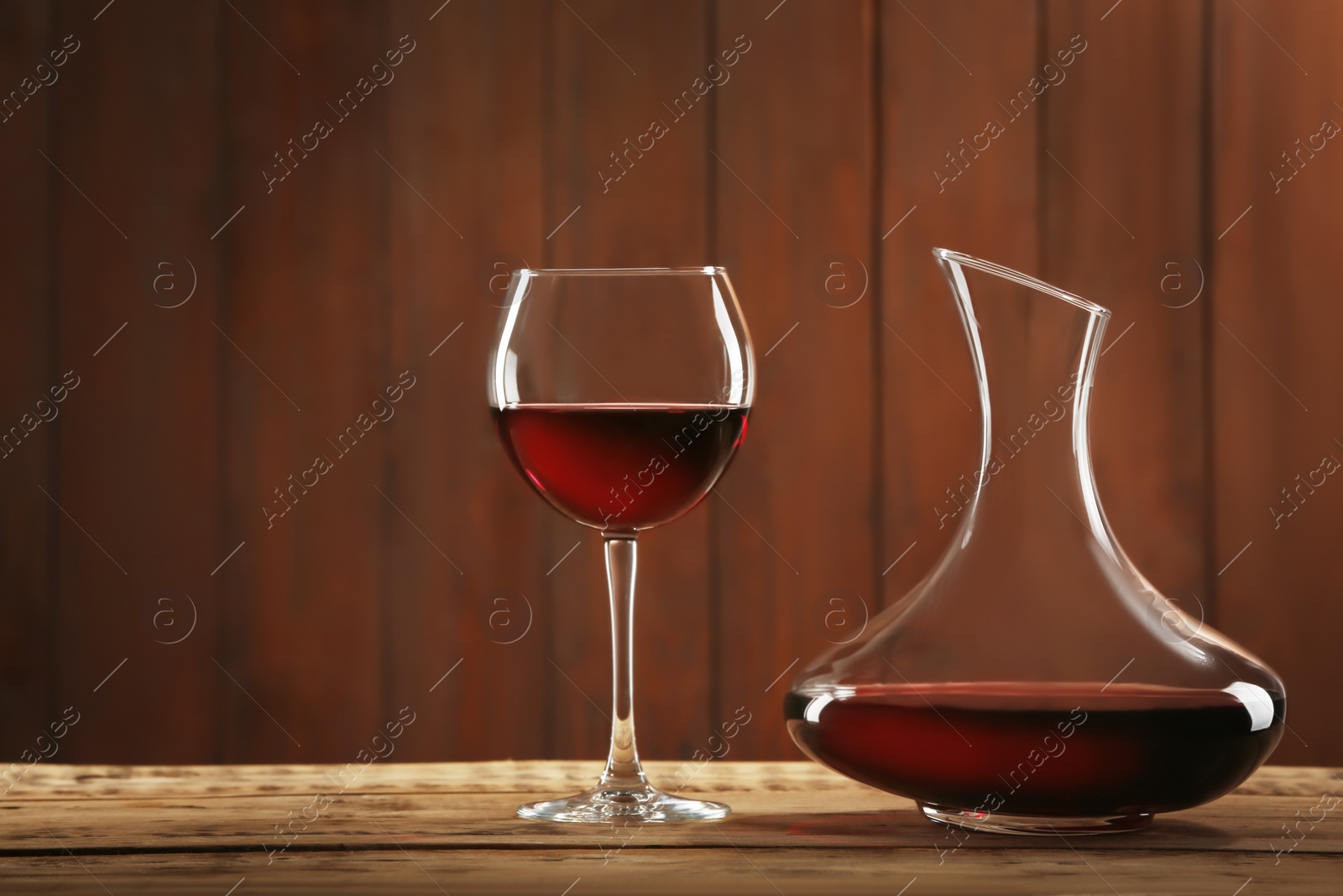 Photo of Elegant decanter and glass with red wine on table against dark background