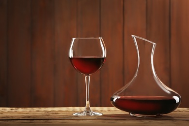 Photo of Elegant decanter and glass with red wine on table against dark background