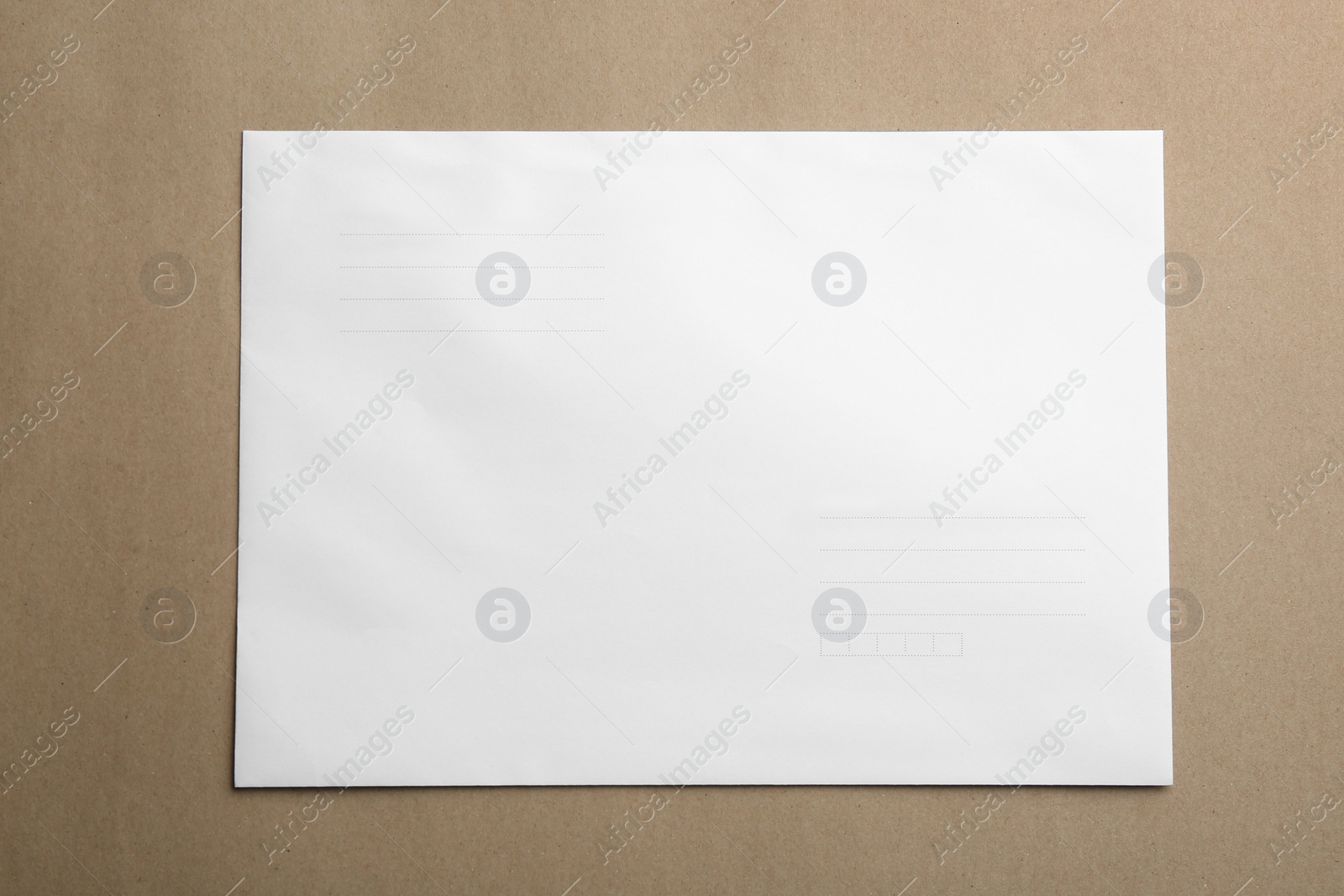 Photo of White paper envelope on brown background, top view