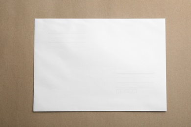 Photo of White paper envelope on brown background, top view